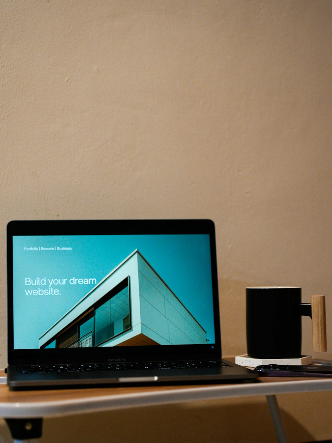 A laptop on top of a table with a coffee mug beside. Build your dream website for your future.